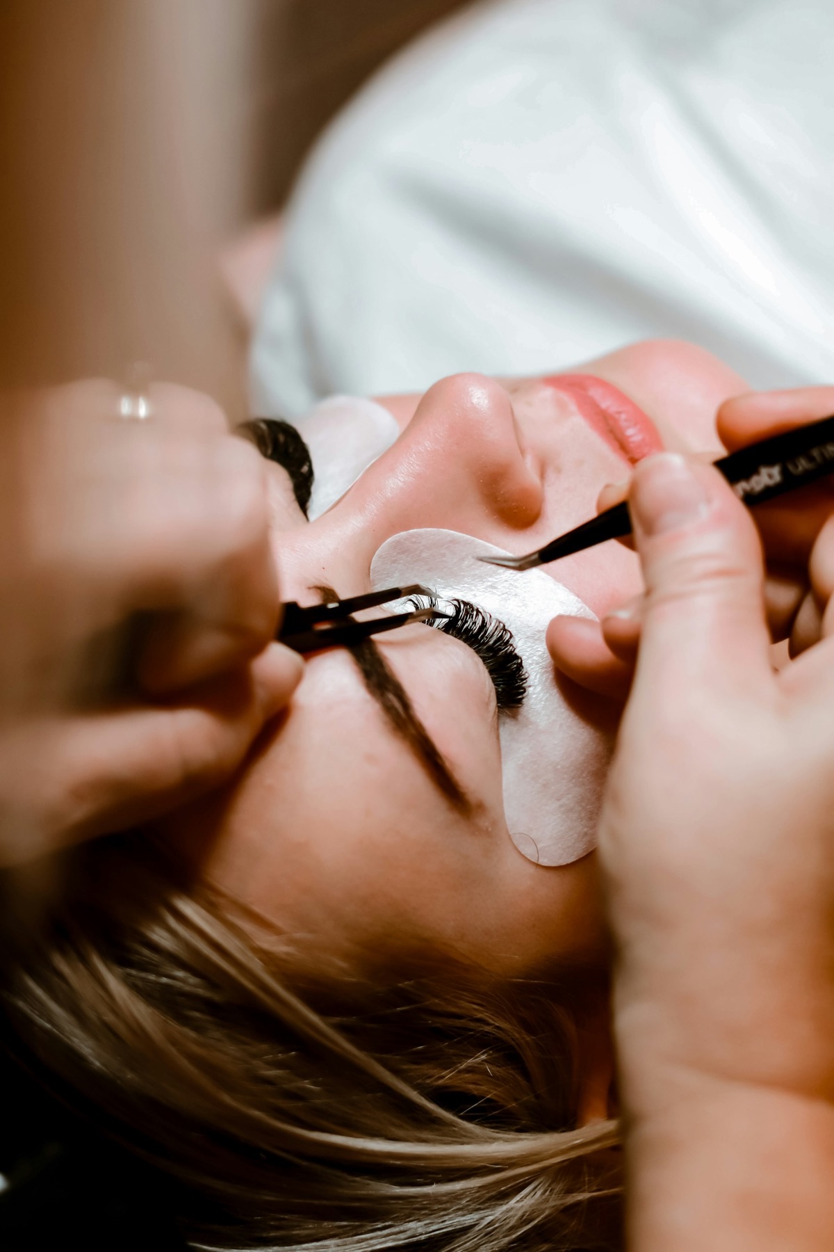 Lash artist applying extensions with tweezers